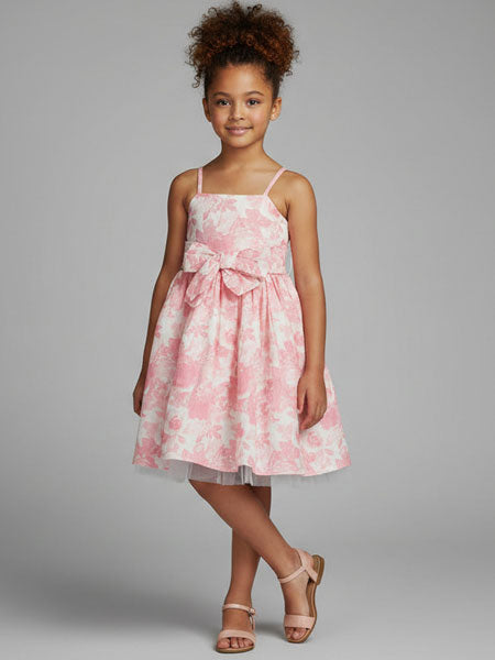 Young girl wearing a pink floral dress with a bow on a gray background