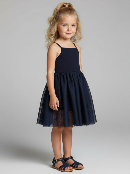 Young girl wearing a navy blue  tutu dress with a sheer overlay on a gray background
