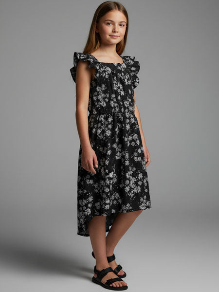 Young girl wearing a black floral dress against a gray background