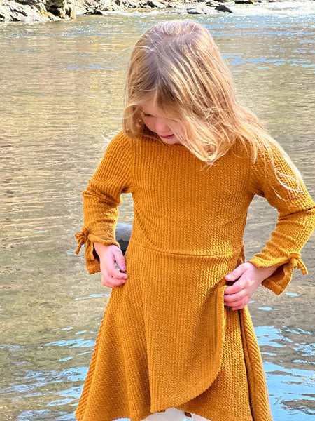 High low faux wrap style dress in pumpkin for girls by Vignette. Cute ties on long sleeves by wrists.