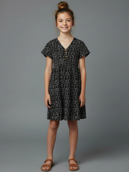 Young girl wearing a black floral dress against a gray background