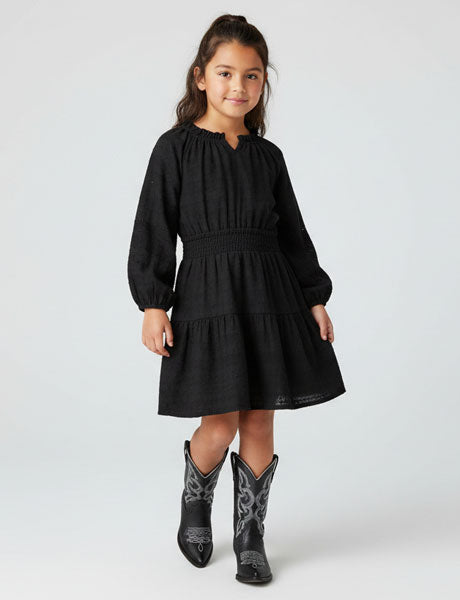 Young girl wearing a black dress and cowboy boots on a white background