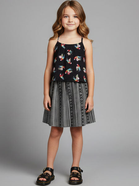 Young girl wearing a black dress with colorful floral pattern on a gray background
