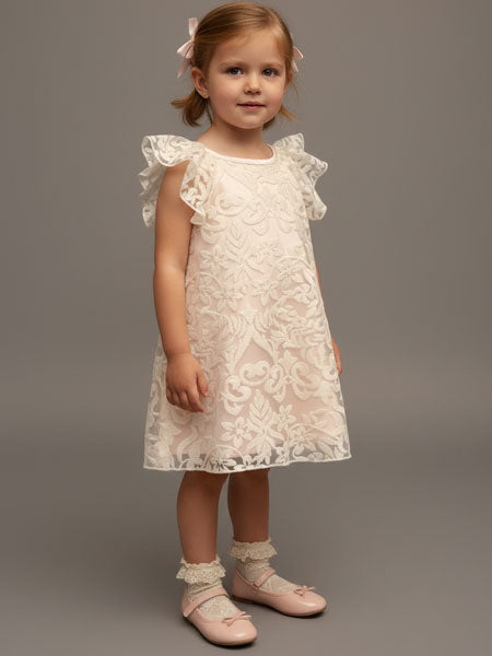 Young girl wearing a white lace dress against a gray background