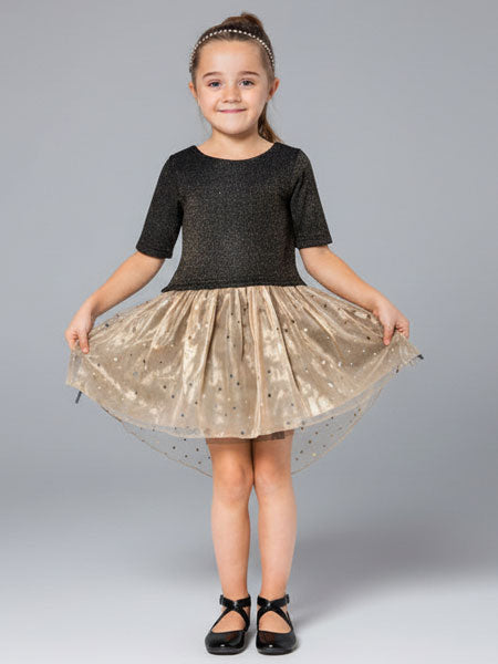 Young girl wearing a black top and gold skirt on a gray background