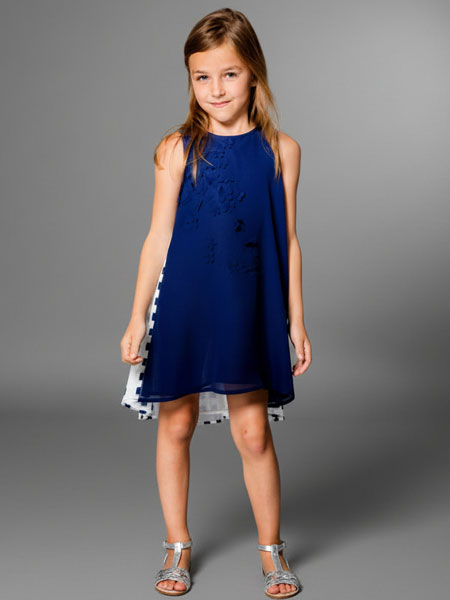 Young girl wearing a blue dress with a gray background