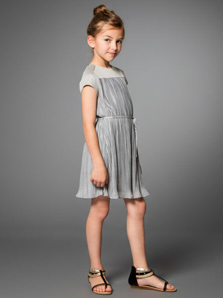 Young girl wearing a gray dress against a gray background