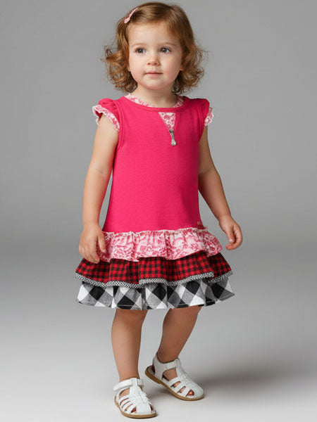 Young girl wearing a pink top with lace details and a plaid skirt on a gray background
