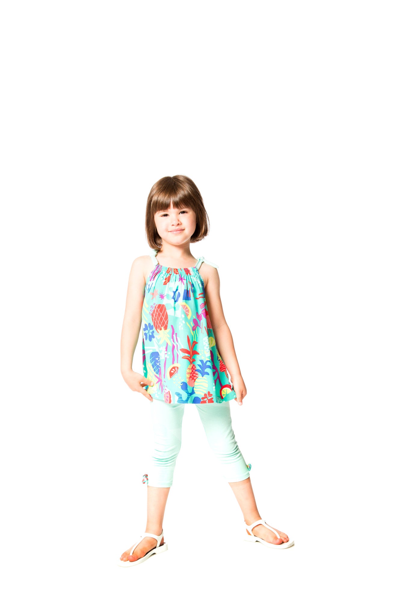 Young girl wearing a colorful dress with floral patterns on a white background