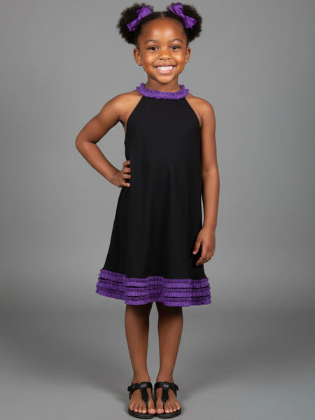 Young girl wearing a black dress with purple trim against a gray background