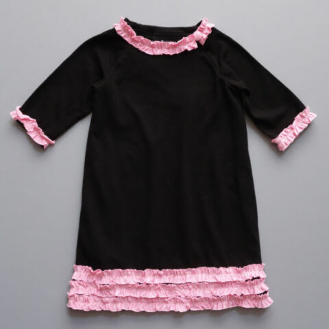 Black jersey knit dress. Pink ruffle trim on collar, sleeves, and hem line. Toddler size shown.