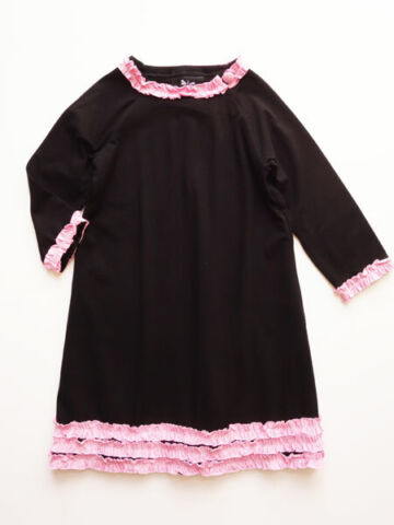 Black jersey knit dress. Pink ruffle trim on collar, sleeves, and hem line.