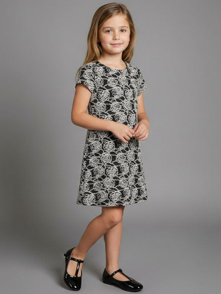 Young girl wearing a black and white patterned dress on a gray background