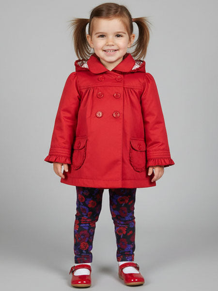 Child wearing a red coat with floral leggings on a gray background