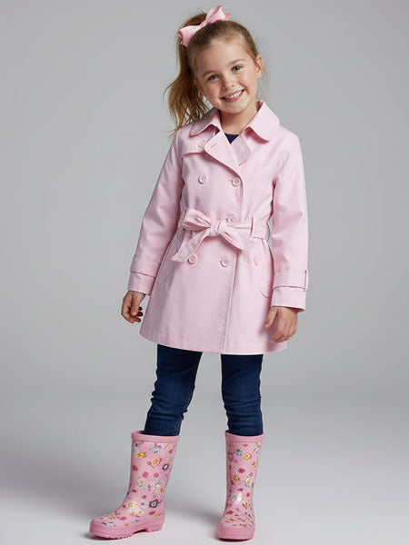 Young girl wearing a pink coat and rain boots on a gray background