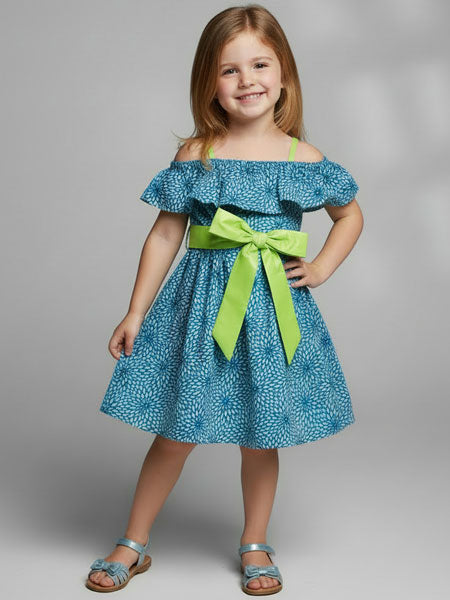 Young girl wearing a blue dress with a green bow on a gray background