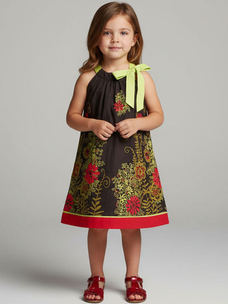 Young girl wearing a floral dress with a green bow on a plain background
