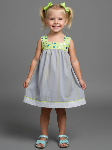 Young girl wearing a gray dress with green accents against a gray background