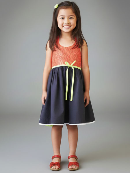 Young girl wearing a red and navy dress with a yellow ribbon on a gray background