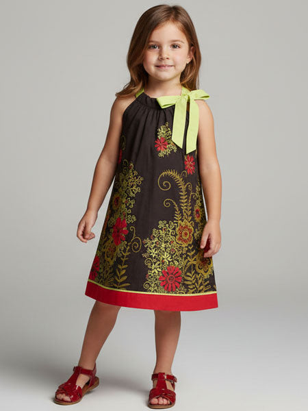 Young girl wearing a floral dress with a green bow on a gray background