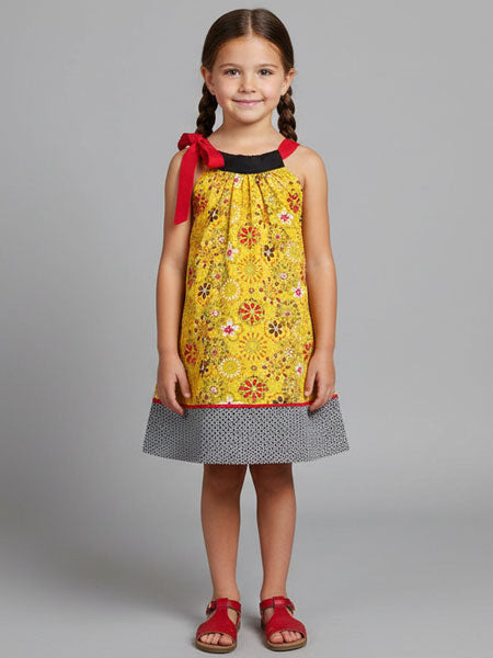 Young girl wearing a yellow floral dress with red accents on a gray background