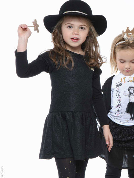 Little girl wearing embossed pattern jersey dress. Black. Long sleeves, layered look. Drop waist.