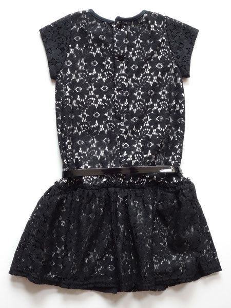 Back view of black lace girls party dress. Drop waist style with patent leather belt at natural waist. Short cap sleeves, white lining visible under lace.