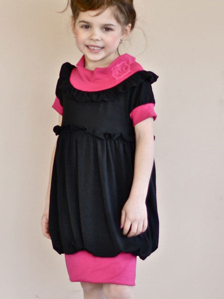 Black jersey dress with pink accent material. Banded neckline adjusts high or towards shoulders. For toddler and little girls.