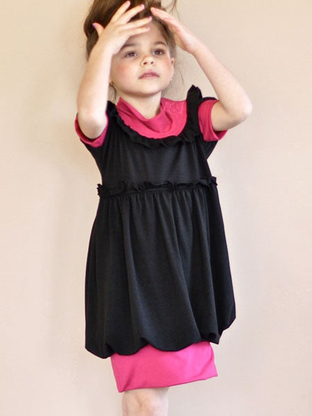 Black jersey dress with pink accent material. Banded neckline adjusts high or towards shoulders. For toddler and little girls.