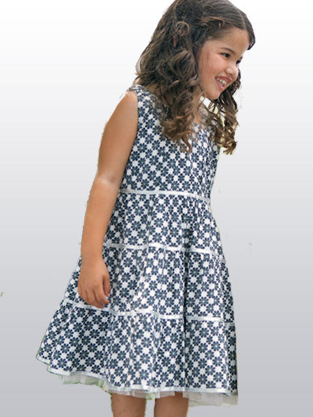 Little girl model i n a slate gray and white abstract clover print dress. Tiered. Metallic ribbon and thread accents. Sleeveless.