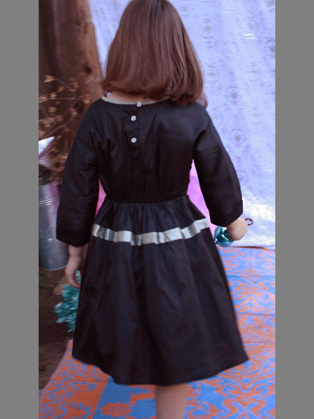 Black shantung silk taffeta dress for girls. Cuffed sleeve, elastic waist, with full skirt. Back view.